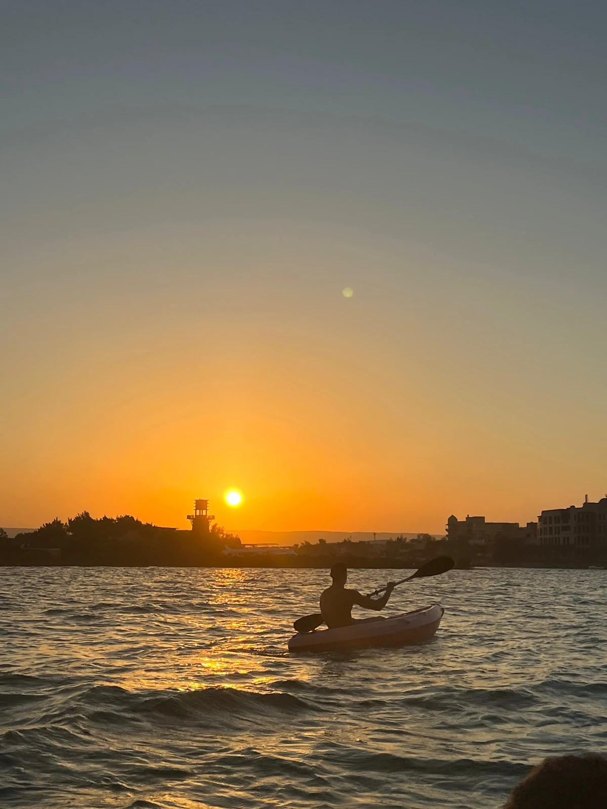 Kayaking — paddling across the water at sunset